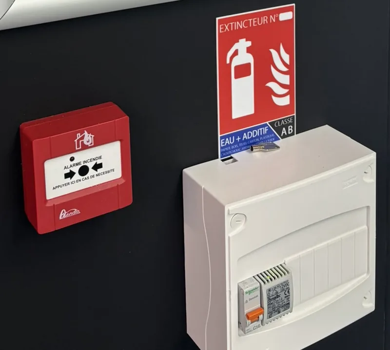 Détail du déclencheur manuel rouge et de la signalétique d’un extincteur installés sur place.