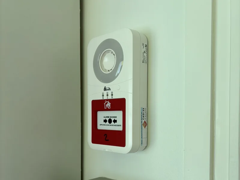 Alarme incendie avec diffuseur sonore et déclencheur manuel rouge, installée dans des locaux professionnels.